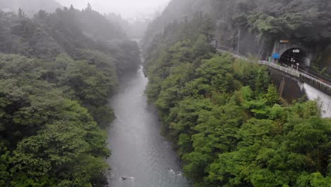 Ascending-drone-shot-over-a-river-on-a-misty-foggy-rainy-day