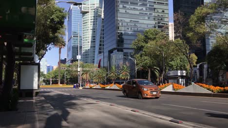 Blick-Auf-Die-Allee-Paseo-De-La-Reforma-Mit-Verkehr-Von-Einer-Bushaltestelle-Mit-Dem-Kreisverkehr-Der-Palme-Und-Gebäuden-Im-Hintergrund,-Mexiko-Stadt