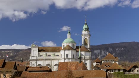 Tiro-De-Lapso-De-Tiempo-De-La-Histórica-Catedral-De-La-Iglesia-Y-Nubes-En-Movimiento-En-El-Cielo-Azul-En-El-Fondo-En-Solothurn,-Suiza