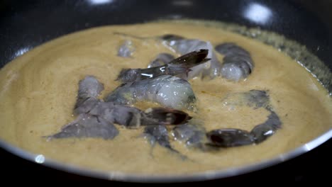 Adding-Raw-Fresh-Blue-Grey-colored-Shrimps-into-Asian-Yellow-Coconut-Cream-Curry