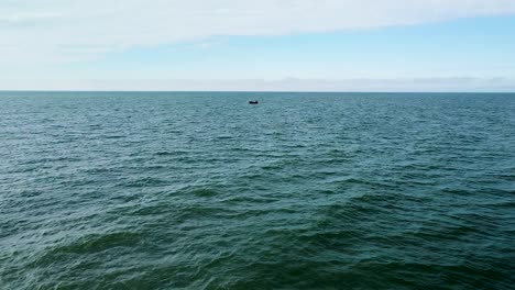 Beautiful-aerial-view-of-a-distant-fishing-boat-sailing-in-the-calm-Baltic-sea-in-sunny-day,-wide-angle-drone-shot-moving-forward