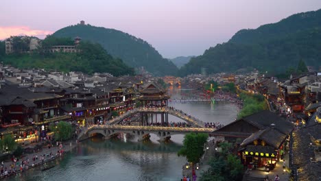 Sonnenuntergang-über-Der-Historischen-Steinbrücke-über-Den-Tuojiang-Fluss-Tuo-Jiang-Fluss-Und-Traditionelle-Chinesische-Architektur-Von-Holzhäusern-In-Der-Antiken-Altstadt,-Bekannt-Als-Phoenix-Ancient-Town