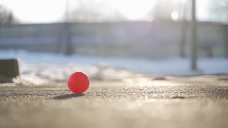 Small-red-ball-on-icy-pavement-in-winter