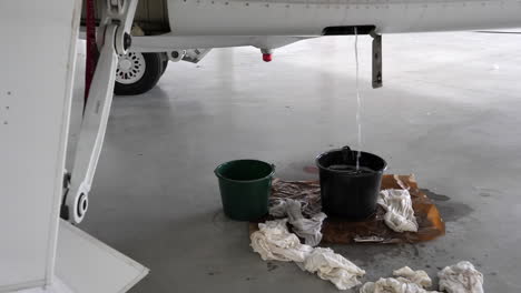 Kerosene-Fuel-Draining-out-of-Hangared-Aircraft's-Drain-in-Bucket