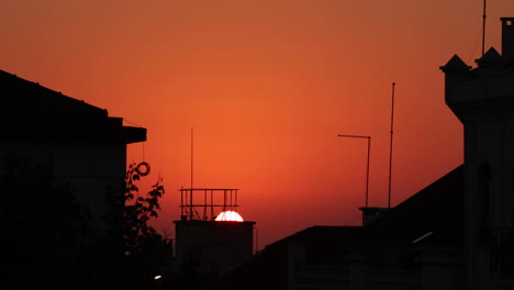 Sonnenuntergang-Zur-Goldenen-Stunde-Hinter-Einem-Gebäude-Mit-Rotem-Himmel-In-Nazare,-Portugal---Nahaufnahme
