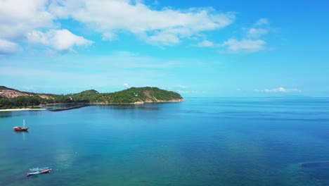 Pacífica-Laguna-Azul-Turquesa-Con-Barcos-De-Pesca-Flotando-En-Aguas-Tranquilas-Que-Reflejan-Un-Cielo-Brillante-Con-Nubes-Blancas-En-Tailandia