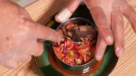 Essen-Anrichten---Koch-Mit-Handschuhen-Hält-Einen-Löffel-Und-Drückt-Das-Thunfisch-Ceviche-Auf-Einen-Keramikteller