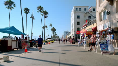 Sunny-Summer-Day-on-Venice-California-Boardwalk,-Blue-Skies-over-People-Walking