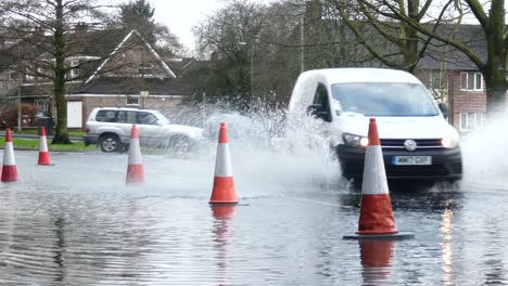 Storm-Christoph-vans-driving-rainy-heavy-flooded-village-road-splashing-street-cones
