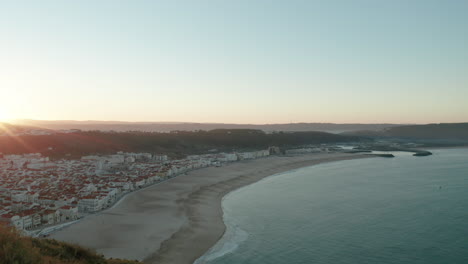 Medieval-Urban-Landscape-By-The-Serene-Ocean-During-Sunrise-At-North-Beach-In-Nazare,-Portugal