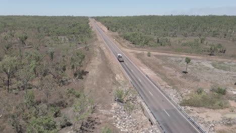 Still-Drone-shot-of-a-truck-driving-on-a-long-straight-highway-in-Northern-Territory,-Australian-Outback