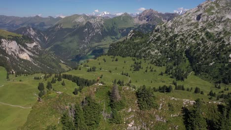 Drone-shot-flying-over-a-man-standing-by-himself-alone-on-the-top-of-the-hill,-looking-over-the-epic-and-vast-landscape-in-Seebergsee,-Switzerland