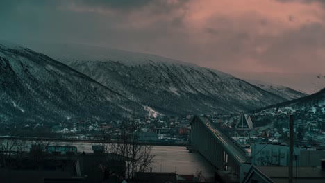 Timelapse-showing-the-bridge-in-Tromso-under-a-crazy-winter-sunset,-clouds-and-sunlight-mixing-like-crazy