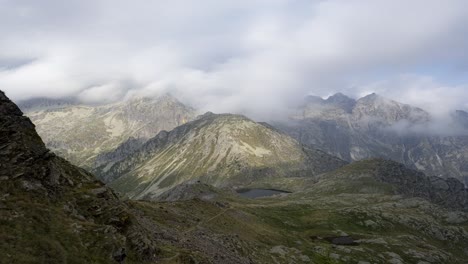 Clouds-rushing-over-the-landskape-in-the-mountains-of-Lagorai,-Italy,-looking-down-at-small-lakes-and-rocky-hillsides