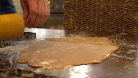 Flattening-gingerbread-dough-with-rolling-pin-on-a-floured-table