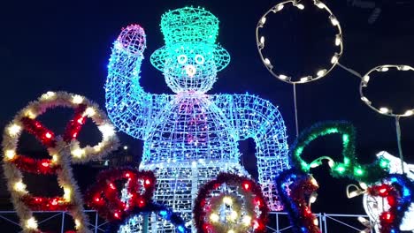 Giant-Snowman-decorations-lite-up-outdoors,-at-night