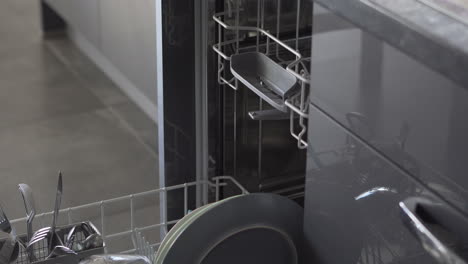 Mann-Nimmt-Das-Saubere-Geschirr-Aus-Der-Spülmaschine
