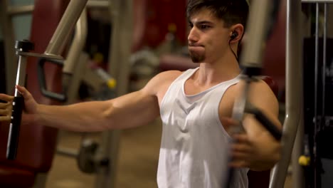 Extreme-closeup-of-teen-bodybuilder-doing-vertical-deltoid-fly-exercises-on-a-machine-at-a-fitness-gym