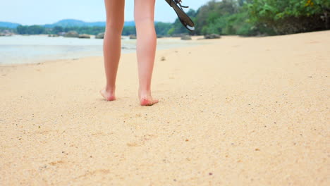 A-beautiful-girl-is-taking-a-walk-barefoot-on-a-sandy,-exotic-beach-in-asia