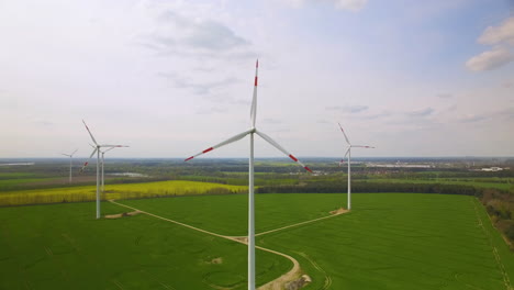 Aerial-view-of-Windmills-in-a-big-green-cultivated-land-for-agriculture,-Sunny-blue-sky-with-clouds