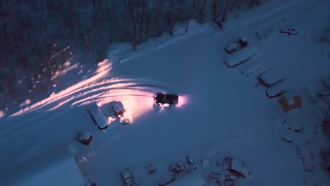 A-birds-eye-view-of-a-custom-built-off-road-miata-car-doing-some-donuts-in-a-fresh-snowy-parking-lot