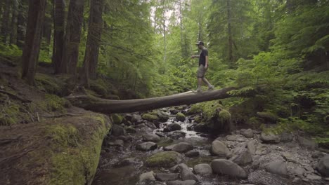 Slow-motion-man-crossing-over-stream-in-the-forest-in-the-Pacific-Northwest