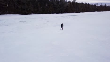 A-man-auger's-a-hole-for-ice-fishing-on-Fitzgerald-Pond,-Maine