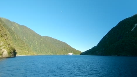 Wide-shot-of-a-cruises-ship-in-a-fiord-between-tall-mountains,-Milford-Sound,-New-Zealand