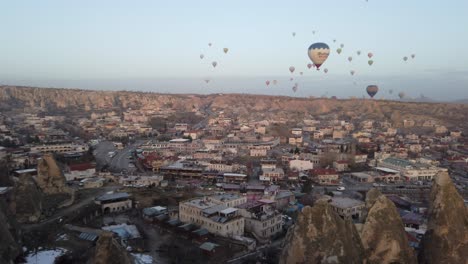Panning-shot-of-Goreme-town-with-colourful-hot-air-balloons-in-the-sky,-Cappadocia,-Turkey