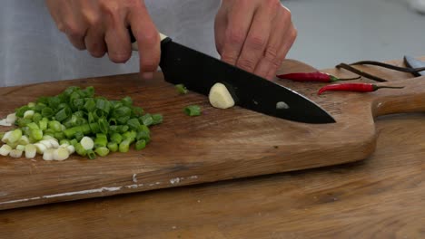 Slicing-a-glove-of-garlic-among-celery-and-chillies-on-a-cutting-board