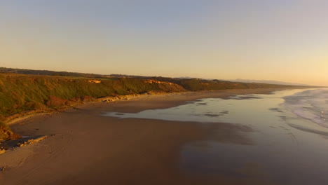 Aerial-footage-drone-flying-forwards-over-Whiskey-Run,-a-beach-near-Bandon-at-the-Southern-Oregon-coast-during-sunset