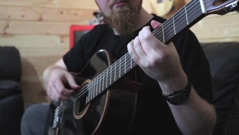 Bearded-man-playing-black-acoustic-guitar,-finger-style-Medium-Shot