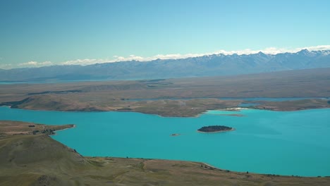 Cámara-Lenta---Hermoso-Glaciar-Azul-Lago-Tekapo,-Nueva-Zelanda-Desde-Un-Avión-De-Vuelo-Panorámico-Con-Montañas-En-El-Fondo