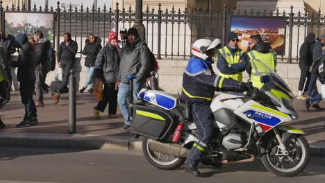 A-police-officer-with-a-helmet-turns-on-his-motorbike-and-lives-the-scene-while-yellow-jacket-protesters-awaiting-for-the-demonstration-to-begin-talk-peacefully-in-Marseille,-south-of-France
