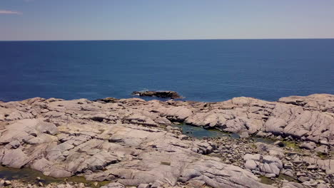 Beautiful-flyover-of-a-rocky,-rugged-shoreline-along-the-Atlantic-Coast-in-Nova-Scotia,-Canada-on-a-bright,-sunny-day
