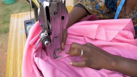 Close-up-shot-from-above-of-an-African-womans-hands-as-she-sews-clothing-with-a-tailoring-machine