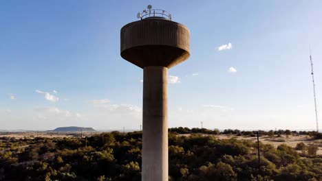 DRONE-Reveal-Shot-of-a-Broadcast-Tower-in-a-Rural-Area-on-a-Sunny-Day