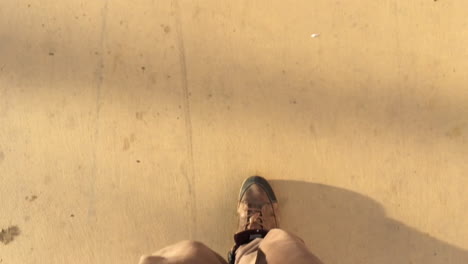 Vertical-closeup-of-man-legs-and-big-shoes-walking-in-slow-motion-with-morning-shadow