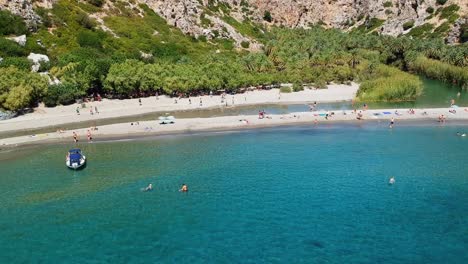 A-heavenly-beach-and-lagoon-with-taxi-boats-and-yachts-visiting-from-nearby-villages,-Preveli-beach-and-palm-forest,-Crete