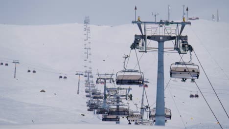 Long-6-person-ski-lift-with-a-cable-car-intersection-during-a-winter-morning-in-Gudauri-Ski-Resort,-Georgia