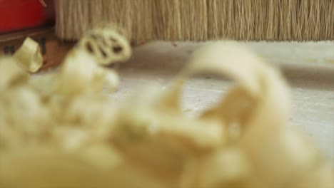 A-Macro-shot-of-Planned-wood-shavings-being-swept-away-by-a-Carpenter-in-slow-motion