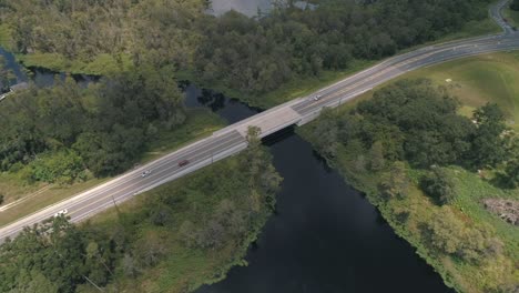 Filmischer-Drohnenclip-Der-Straßenbrücke-Am-Seeufer-über-Den-Kanal,-Der-Den-Lake-Minnehaha-Mit-Dem-Lake-Susan-In-Clermont,-Florida,-Verbindet