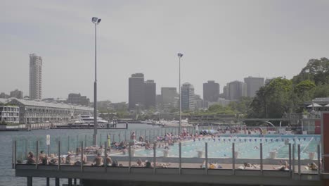 Wide-shot-of-a-public-swimming-pool-with-a-lot-of-people-swimming-during-a-sunny-summer-day