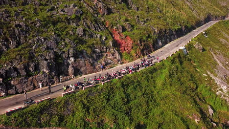 Drone-view-of-a-group-of-motorcyclists-resting-and-taking-photos-on-the-side-of-the-road,-along-the-Ma-Pi-Leng-Pass