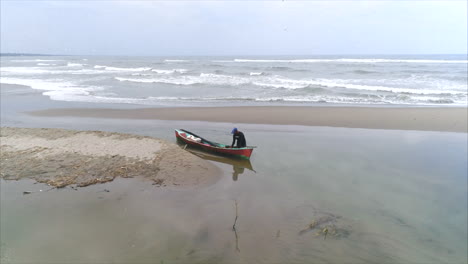 AERIAL:-Honduran-fisherman-arriving-to-the-beach-with-his-canoe-and-picking-up-his-catch