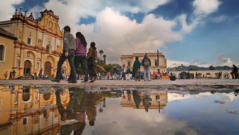 MAIN-CATHEDRAL-AND-RAIN-REFLECTION-ON-THE-FLOOR-IN-SAN-CRISTOBAL-DE-LAS-CASAS,-CHIAPAS-MEXICO-SHOT-PEOPLE-PASSING-BY