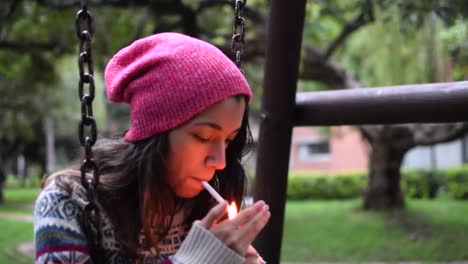 Mujer-Joven-Fumando-Un-Cigarrillo-En-Un-Columpio