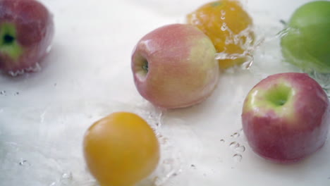 Slomo-Von-Äpfeln-Und-Orangen-Im-Wasser-Auf-Weißem-Hintergrund