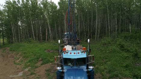 Pull-back-aerial-view-of-water-well-drilling-rig-and-operator-in-rural-setting