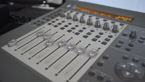 Dolly-away-from-sound-mixing-console-as-faders-move-on-their-own